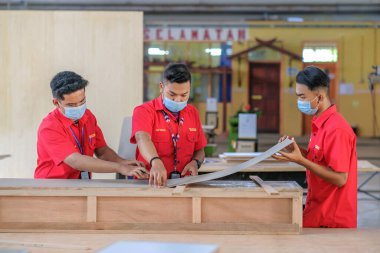 Muadzam Şah, Malezya - 1 Eylül 2020: Atölye atölyelerindeki dolaplara lamine döşeyen genç marangozlar