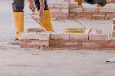 Üniversite öğrencileri tuğla örme atölyesinde tuğla duvar inşaatında çalışıyor.