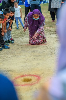 Muadzam Shah, Malaysia -   September 16th, 2020 : People playing traditional games called  marble game  at the field during Malaysia Day clipart