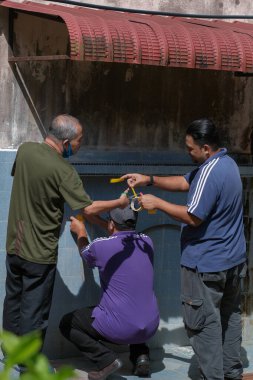 Muadzam Şah, Malezya - 23 Haziran 2020: Erkekler sosyal mesafeyi güvence altına almak için ok ve bant çizgileri yapıyor. Yol tarifi için yerdeki çizgileri işaretle