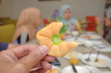 Elinde mavi arka planı olan taze ekmek tutan bir adam.