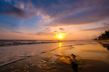 Güneşin doğuşu sırasında kumlu sahilde yumuşak mavi okyanus dalgalarıyla denizin üzerinde güzel bir bulut manzarası.