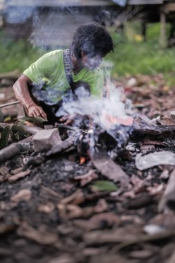 Muadzam Şah, Malezya - 18 Ağustos 2020: Malezya yerlilerinin portresi evin yakınında ateş yakıyor