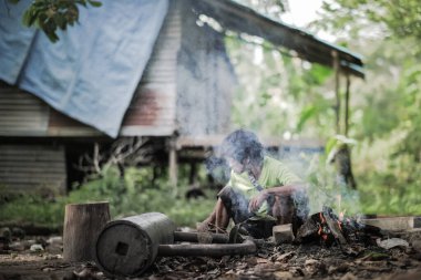 Muadzam Şah, Malezya - 18 Ağustos 2020: Malezya yerlilerinin portresi evin yakınında ateş yakıyor