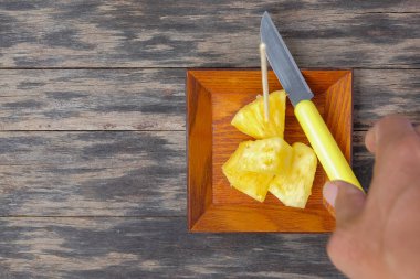 Tahta masada dilimlenmiş ananaslı ahşap tabak. Üst görünüm.