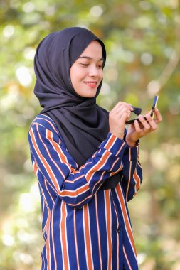 Güzel genç bir kadın fırça ve güzellik konsepti kullanarak yüzüne allık sürüyor.