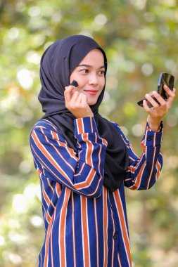 Güzel genç bir kadın fırça ve güzellik konsepti kullanarak yüzüne allık sürüyor.