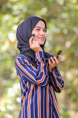 Güzel genç bir kadın fırça ve güzellik konsepti kullanarak yüzüne allık sürüyor.