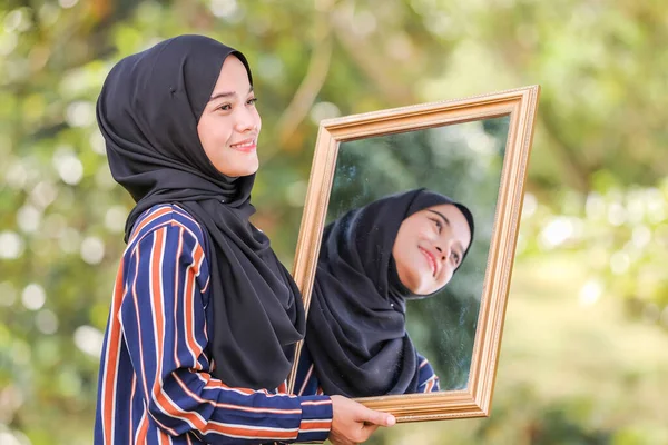 鏡の前でヒジャーブを身に着けている笑顔の美しい若いイスラム教徒の女性の肖像画と屋外で撮影背景がぼやけている ファッションと美容の概念のための使用 — ストック写真