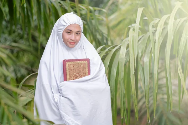 美しいイスラム教徒の女性が緑の木の庭でクルアーンを手に イスラム教育の概念 — ストック写真