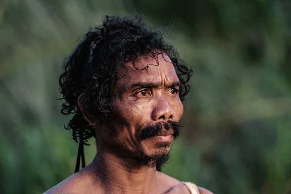 Older Asian men are standing smoking. Orang Asli in a village at Muadzam Shah, Pahang, Malaysia