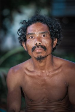 Yaşlı Asyalı adamlar bulanık arka planlı kameraya bakıyor. Orang Aslı, Muadzam Şah, Pahang, Malezya 'da bir köyde.