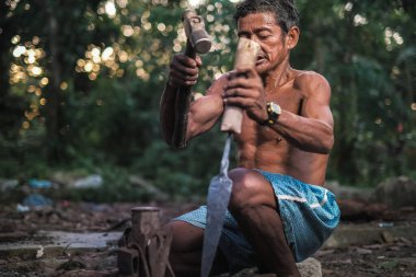 Yerli Malezyalı yerli zanaatkar avlanmak için mızrak yapıyor.