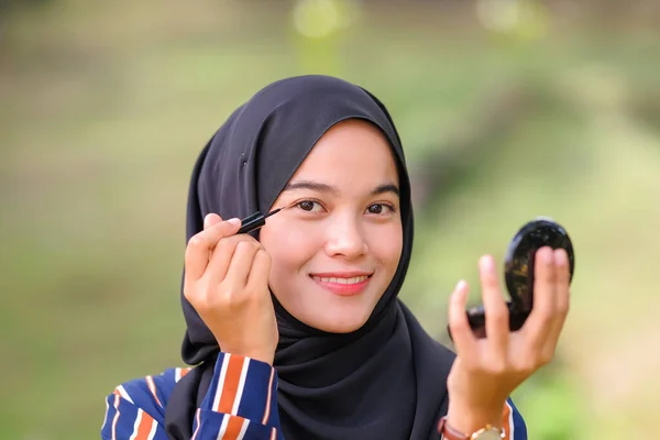 漂亮的穆斯林女孩 头戴黑色头巾 用眼线笔化妆 看着相机 — 图库照片