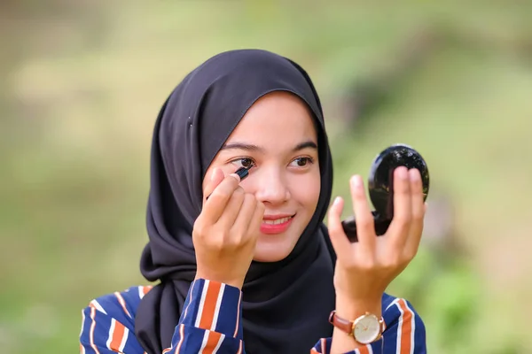 漂亮的穆斯林女孩 头戴黑色头巾 用眼线笔化妆 照镜子 — 图库照片