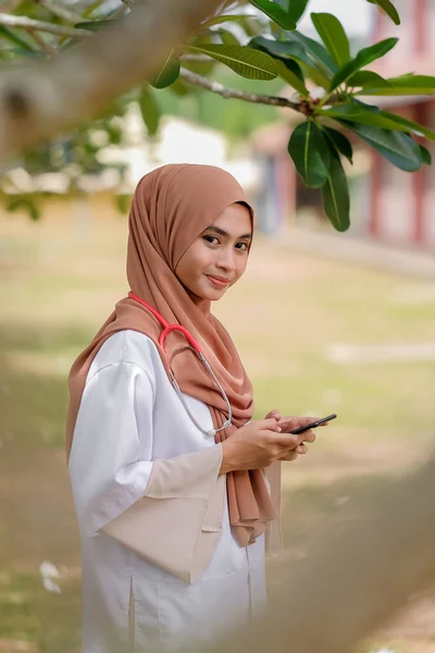 Vrouwelijke Moslimdierenarts Met Een Smartphone Ziekenhuistuin Concept Van Medische Gezondheidsdienst — Stockfoto