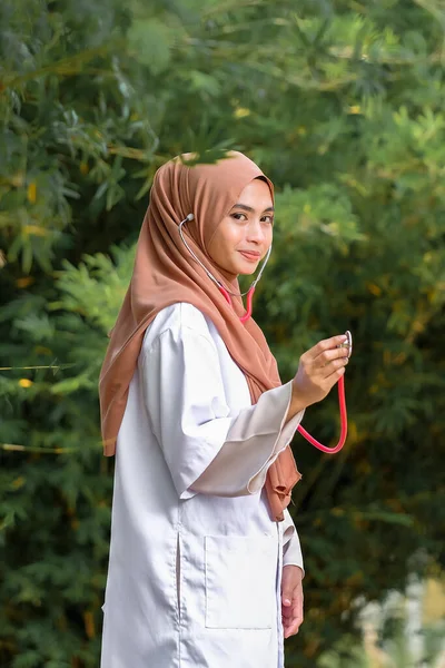 Potret Dokter Wanita Tersenyum Memegang Stetoskop Saat Berdiri Dekat Pohon — Stok Foto