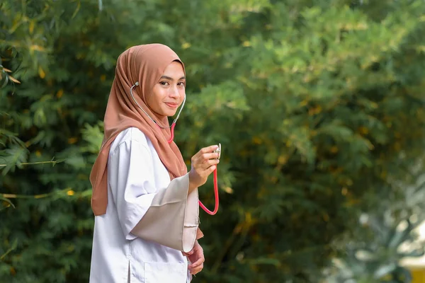 Potret Dokter Wanita Tersenyum Memegang Stetoskop Saat Berdiri Dekat Pohon — Stok Foto