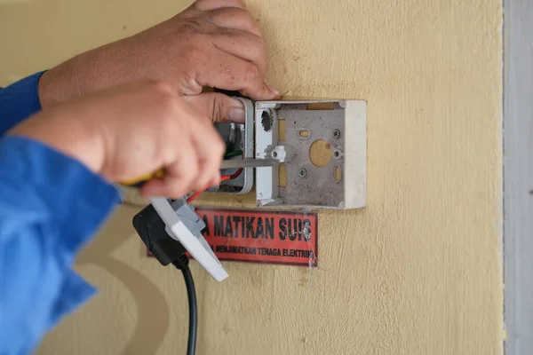 Muadzam Shah, Malaysia- September 28th, 2020 : Electrician installs socket boxes on the wall in workshop.