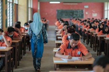 Muadzam Şah, Malezya - 1 Ekim 2020: Soruyu yanıtlayan öğrencisine gülümseyen Müslüman öğretmen
