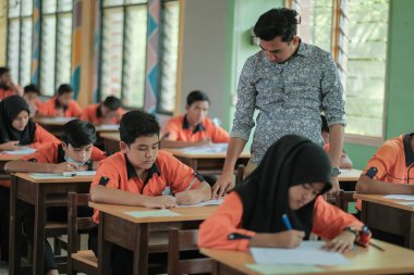 Muadzam Şah, Malezya - 1 Ekim 2020: Soruyu yanıtlayan öğrencisine gülümseyen Müslüman öğretmen