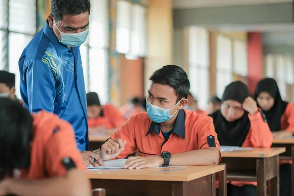 Muadzam Şah, Malezya - 1 Ekim 2020: Soruyu yanıtlayan öğrencisine gülümseyen Müslüman öğretmen