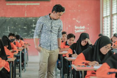 Muadzam Şah, Malezya - 1 Ekim 2020: Soruyu yanıtlayan öğrencisine gülümseyen Müslüman öğretmen