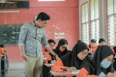 Muadzam Şah, Malezya - 1 Ekim 2020: Soruyu yanıtlayan öğrencisine gülümseyen Müslüman öğretmen