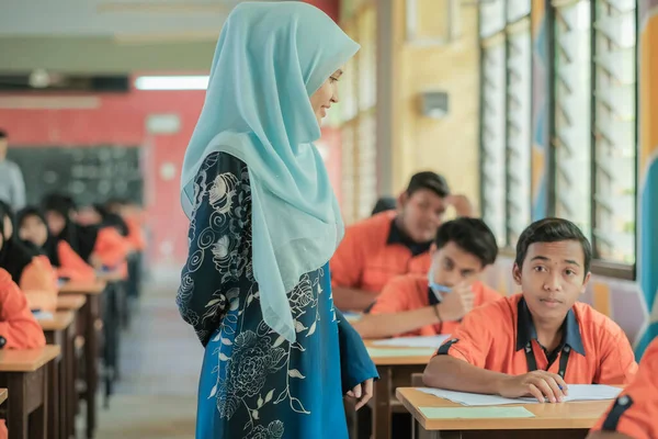 Muadzam Şah, Malezya - 1 Ekim 2020: Soruyu yanıtlayan öğrencisine gülümseyen Müslüman öğretmen