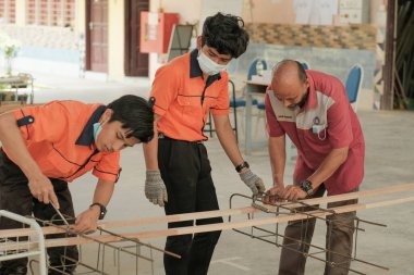 Muadzam Şah, Malezya - 29 Eylül 2020: Konut İnşaat stajyeri ve eğitmeni atölyede demir parmaklıkları bağlıyor.