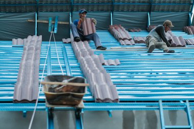 Muadzam Şah, Malezya - 3 Ekim 2020: Kova ve ip kullanarak asansör çatı döşemeleri taşıyan iki işçi