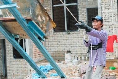 Muadzam Şah, Malezya - 3 Ekim 2020: İşçi işçi kaldırım kiremitlerini kova ve ip kullanarak taşıyor bina çatıları kurun