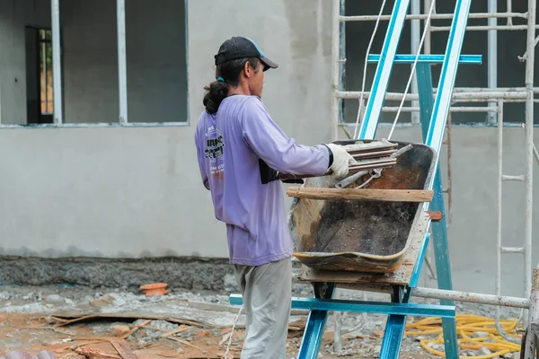 Muadzam Şah, Malezya - 3 Ekim 2020: İşçi işçi kaldırım kiremitlerini kova ve ip kullanarak taşıyor bina çatıları kurun