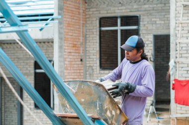 Muadzam Şah, Malezya - 3 Ekim 2020: İşçi işçi kaldırım kiremitlerini kova ve ip kullanarak taşıyor bina çatıları kurun