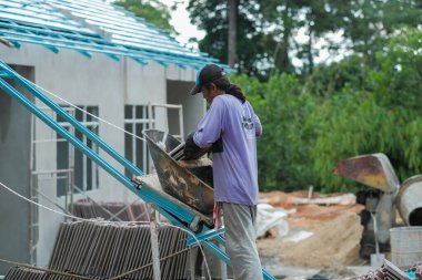 Muadzam Şah, Malezya - 3 Ekim 2020: İşçi işçi kaldırım kiremitlerini kova ve ip kullanarak taşıyor bina çatıları kurun