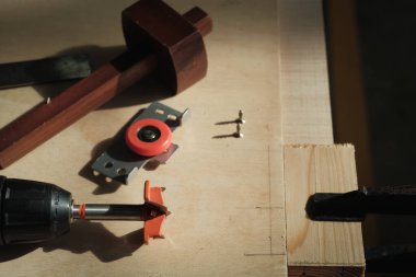 Forstner parçası, sürgülü kapı silindiri, işaretleme göstergesi, vidalar ve ahşap işçilerinin masasında kare deneyin