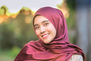 Güzel günbatımında poz veren şık tesettürlü güzel genç modelin portresi. Tarz sahibi Müslüman kadın tesettür moda tasviri.