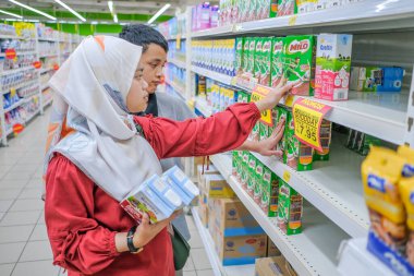 Muadzam Şah, Malezya - 8 Mart 2020: Süpermarkette alışveriş yapan, ürün bilgisi okuyan, süt tutan, fiyatları ve kaliteyi karşılaştıran, günlük giysiler giyen gençler çekici görünümlü.