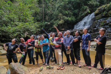 Rompin, Malezya - 11 Ekim 2020: Şelale nehrinin altında eğlenen arkadaşlar grubu. Seyahat ve arkadaşlık kavramı.