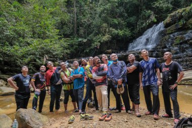 Rompin, Malezya - 11 Ekim 2020: Şelale nehrinin altında eğlenen arkadaşlar grubu. Seyahat ve arkadaşlık kavramı.