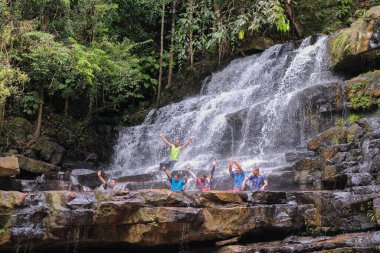 Rompin, Malezya - 11 Ekim 2020: Şelale nehrinin altında eğlenen arkadaşlar grubu. Seyahat ve arkadaşlık kavramı.
