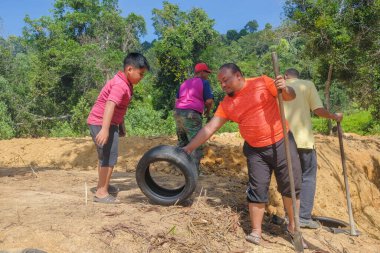 Muadzam Şah, Malezya - 18 Ekim 2020: Bölge sakinleri göl kenarını temizlemek ve temizlemek için birbirlerine takım çalışması ruhuyla yardım ediyorlar. İnsanlar peyzaj işleri yapıyor. .
