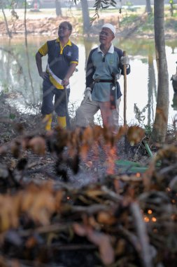 Muadzam Şah, Malezya - 18 Ekim 2020: Bölge sakinleri göl kenarını temizlemek ve temizlemek için birbirlerine takım çalışması ruhuyla yardım ediyorlar. İnsanlar peyzaj işleri yapıyor. .