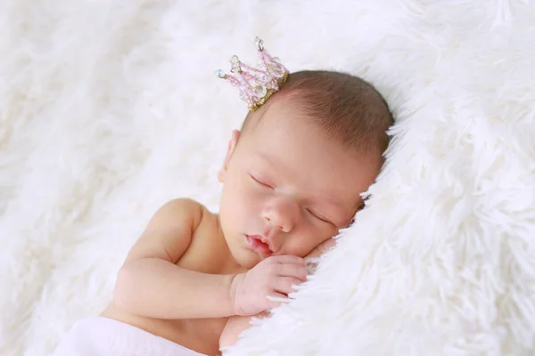 かわいい新生児の女の子が眠っている 王冠の中に生まれたばかりの王女は彼女の頭の下で彼女の腕の上で眠る — ストック写真