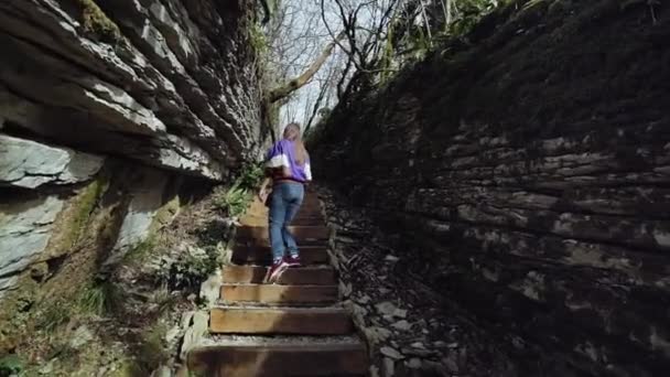 Een meisje klimt de stenen trappen in de berg Rift en verkent de rotsformatie — Stockvideo