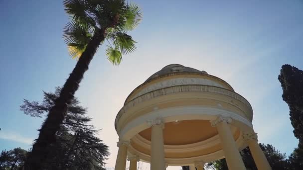 Eine antike Rotunde im Sonnenlicht nahe der Palme. — Stockvideo