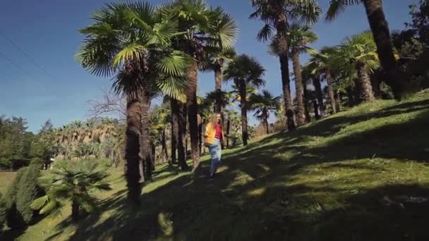 Щаслива дівчина біжить між долонями на сонячних променях — стокове відео