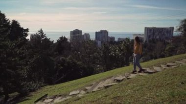 Kız yeşillik ile çevrili, yüksek katlı binaların arka plan üzerinde yeşil bir tepeüzerinde taş merdivenlerden aşağı çalışır