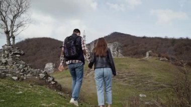 Adam ve kız yeşil bir tepeüzerinde antik taş kale için el ile gitmek