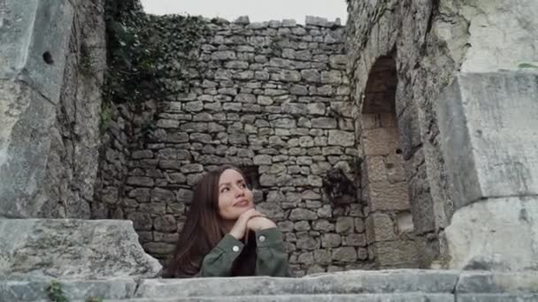 Красивая девушка смотрит в окно древнего замка, как принцесса в крупном плане — стоковое видео